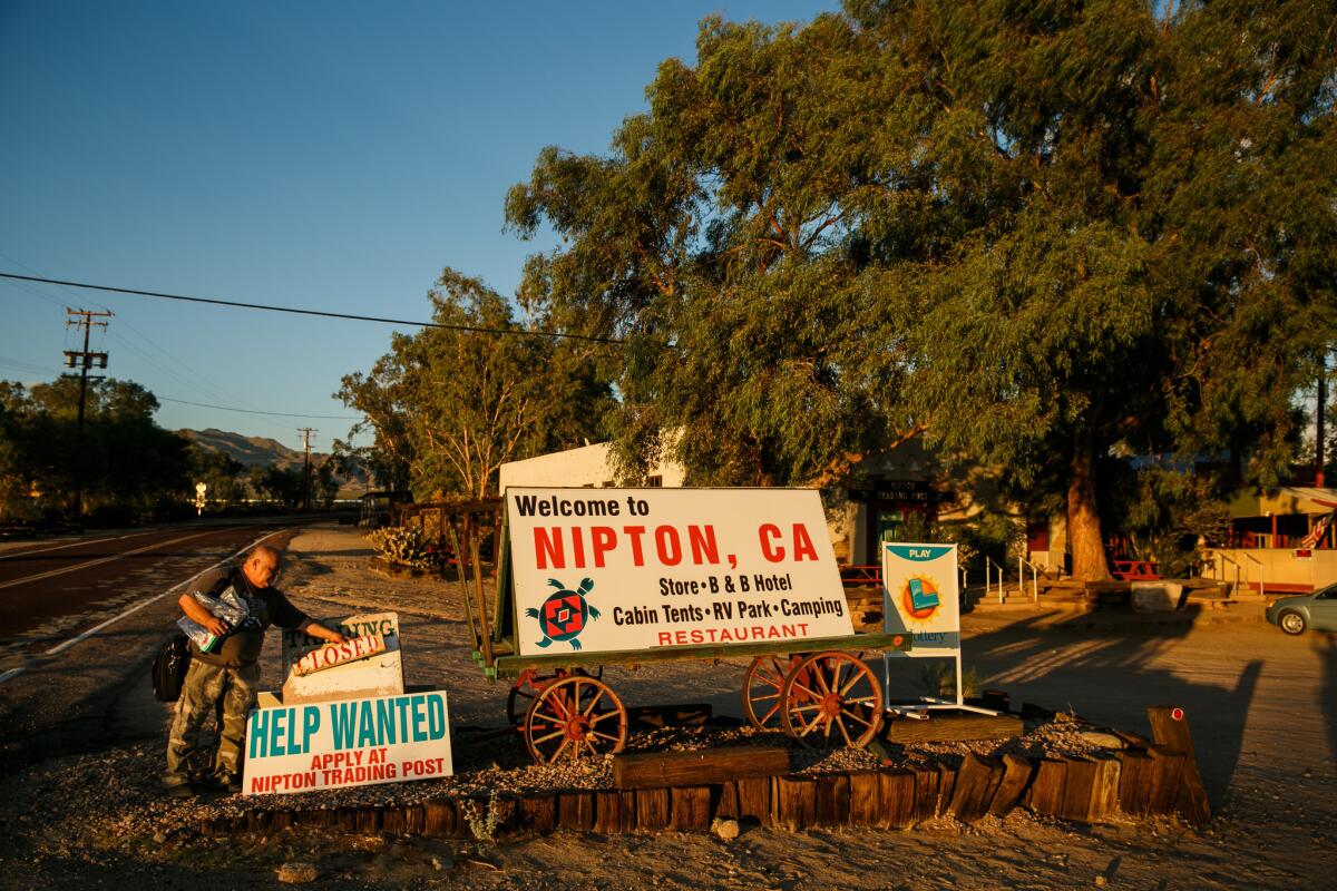 Leo Hernandez changes the "open" sign to "closed" as the trading post closes for the day in Nipton. (Marcus Yam / Los Angeles Times)