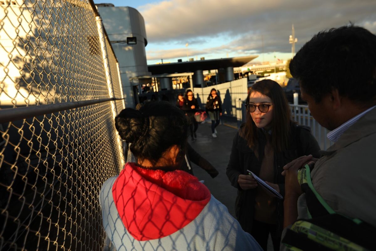 Edith Tapia, a policy research analyst with the Hope Border Institute, center, talks with a Mexican couple and their children who hope to request asylum in the U.S. at the foot of an international Bridge in Ciudad Juarez, Mexico.