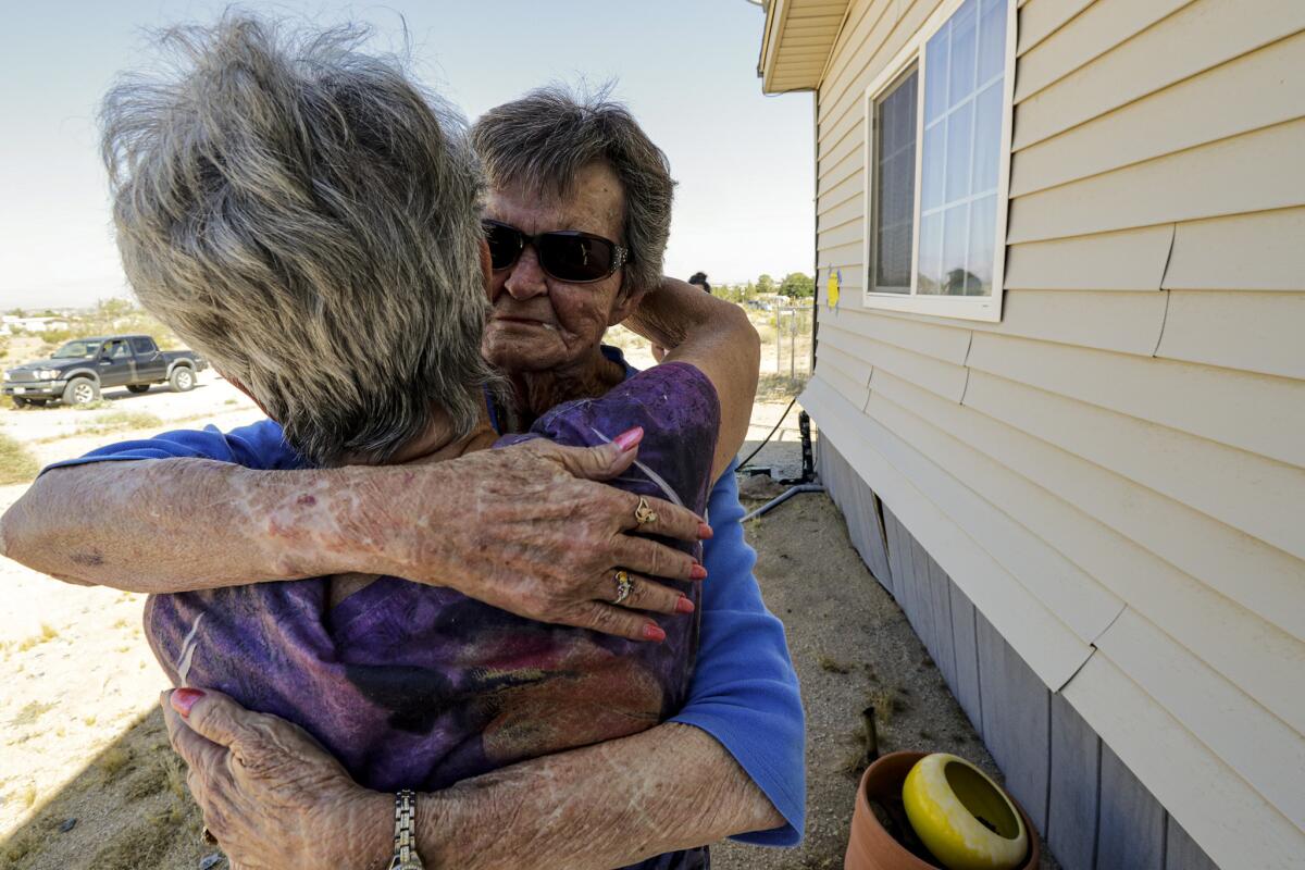 Kathy Vander Housen hugs her friend Claire Barker after Barker said that she had found her two cats after the earthquake.