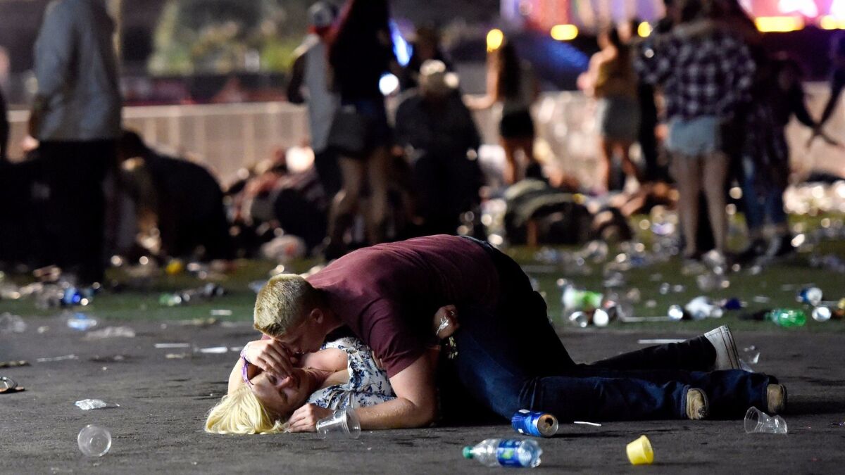 A man lays on top of a woman as others flee the Route 91 Harvest country music festival grounds. Eyewitnesses describe the harrowing scene that left more than 20 people dead and more than 100 others injured.
