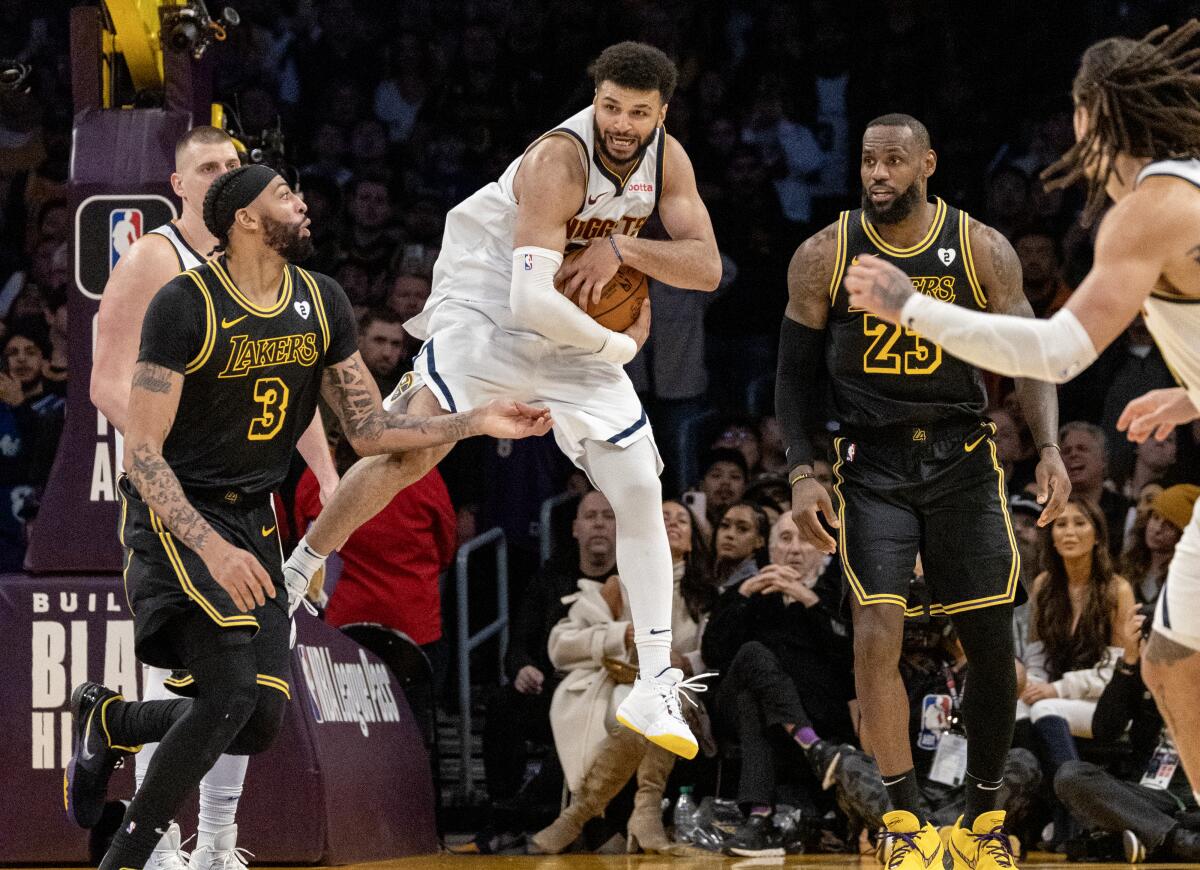 Nuggets guard Jamal Murray leaps to grab a defensive rebound in front of Lakers forwards Anthony Davis and LeBron James.