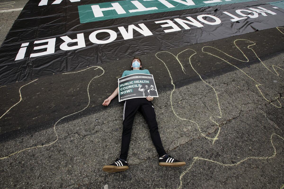 A protester lies on Temple Avenue during a die-in rally by essential workers
