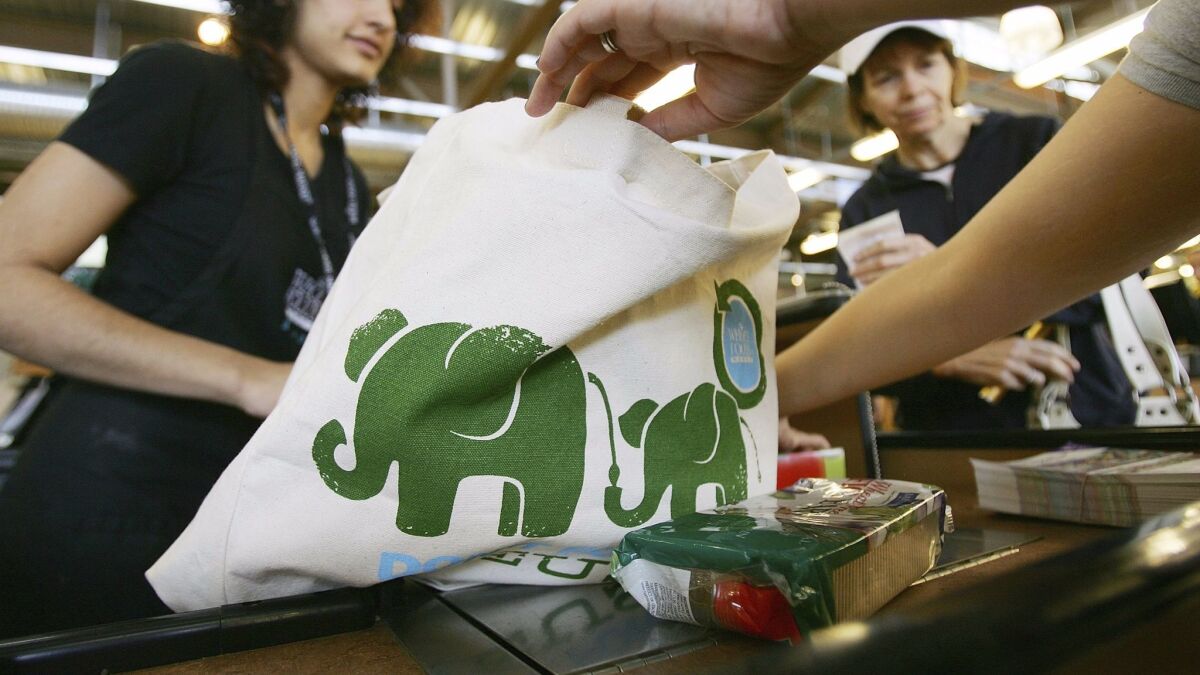 A cashier hands out free reusable grocery bags at a Whole Foods Market in Pasadena, Calif. on April 22, 2008.