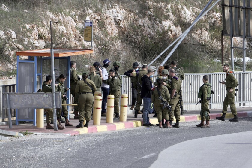 Soldados israelíes se congregan en una parada de autobús en la que un hombre intentó agredir a un grupo de personas en una intersección cerca del asentamiento de Giti Avishar, en Cisjordania, el viernes 31 de diciembre de 2021. (AP Foto/Majdi Mohammed)