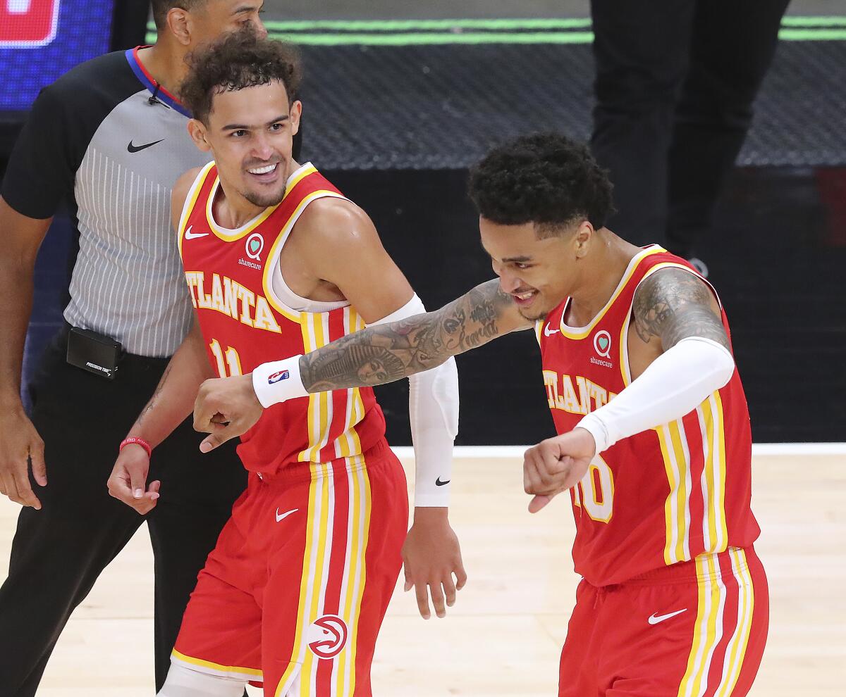 Atlanta Hawks Trae Young, left, celebrates with John Collins after Collins hit a three pointer in the final minute of an NBA basketball game against the Washington Wizards Wednesday, May 12, 2021, in Atlanta. (Curtis Compton/Atlanta Journal-Constitution via AP)