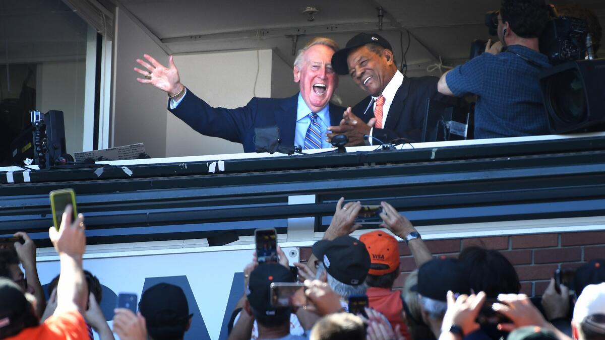Dodgers broadcast announcer Vin Scully and Giants legend Willie Mays wave to the crowd during Scully's final game in the booth.