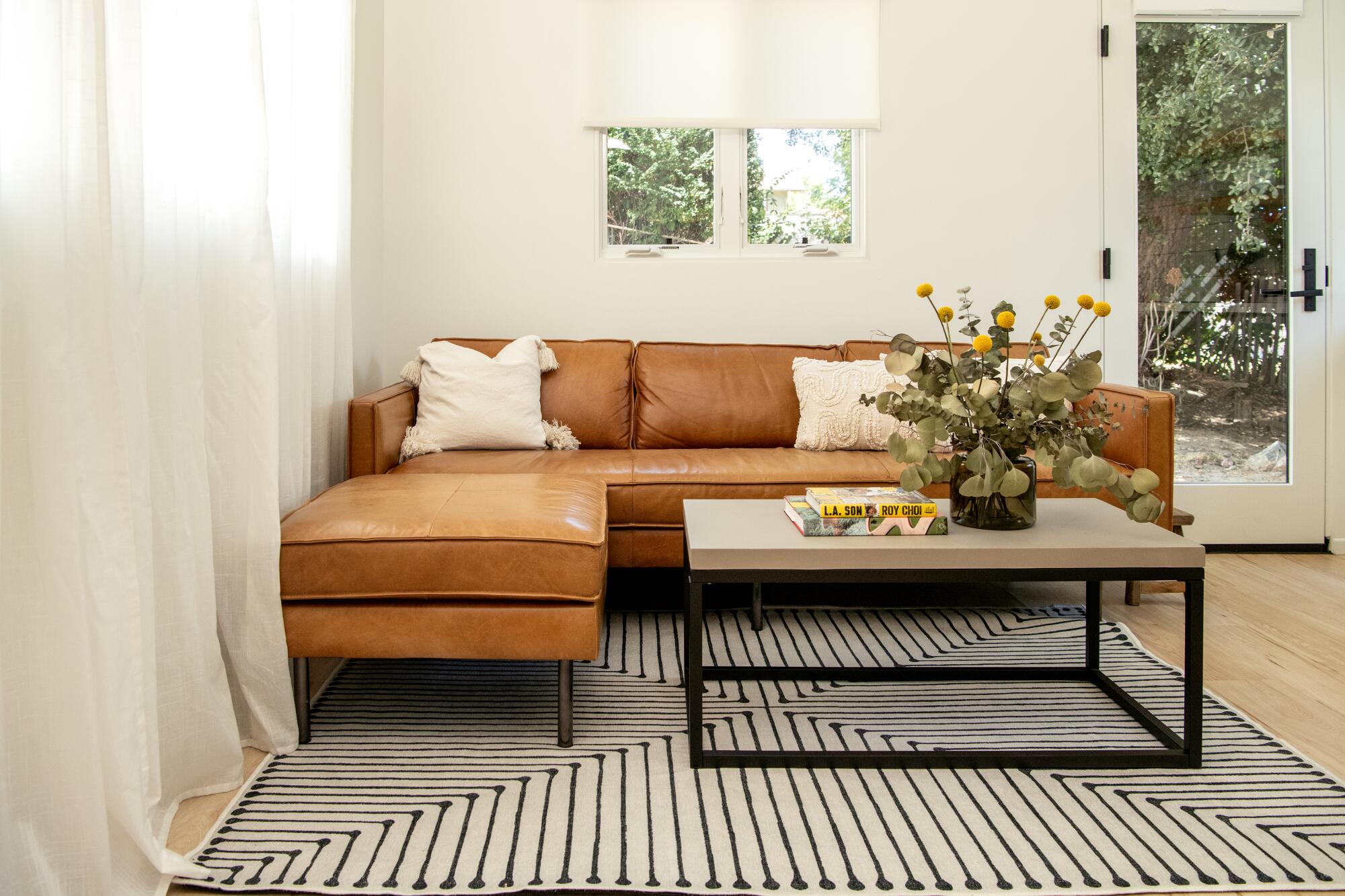 A black and white striped rug, brown leather couch and modern coffee table accent the ADU's living room.