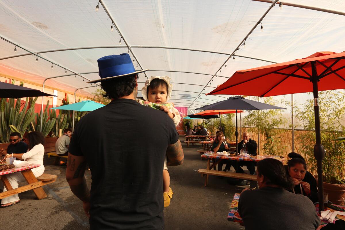 Gilberto Marquez, with 11-month-old daughter Cynthya, walks to their table at Guelaguetza in Koreatown.