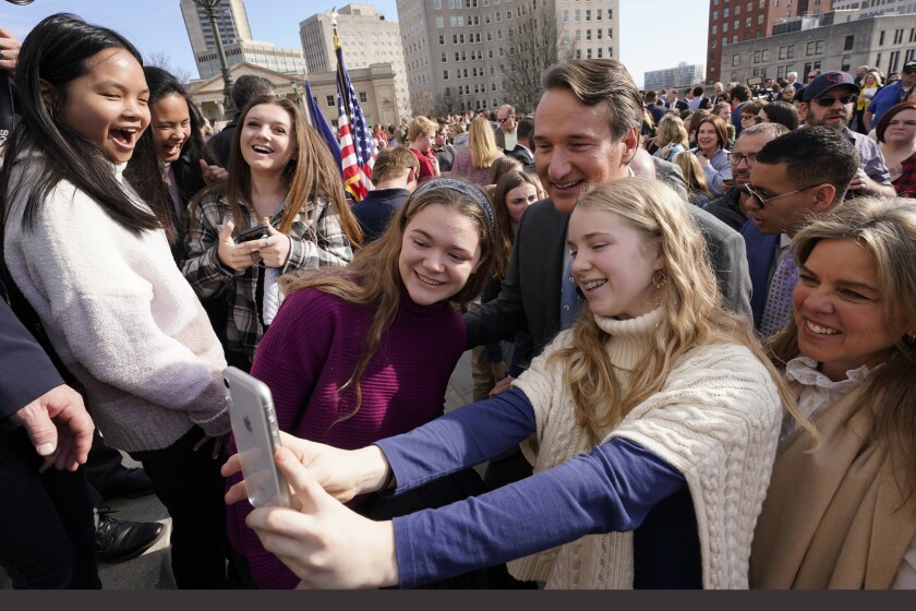 Virginia Gov. Glenn Youngkin, center, and his wife, Suzanne, right, pose for photos with school children and parents after signing a bill that bans mask mandates in public schools in Virginia on the steps of the Capitol Wednesday Feb. 16, 2022, in Richmond, Va. (AP Photo/Steve Helber)