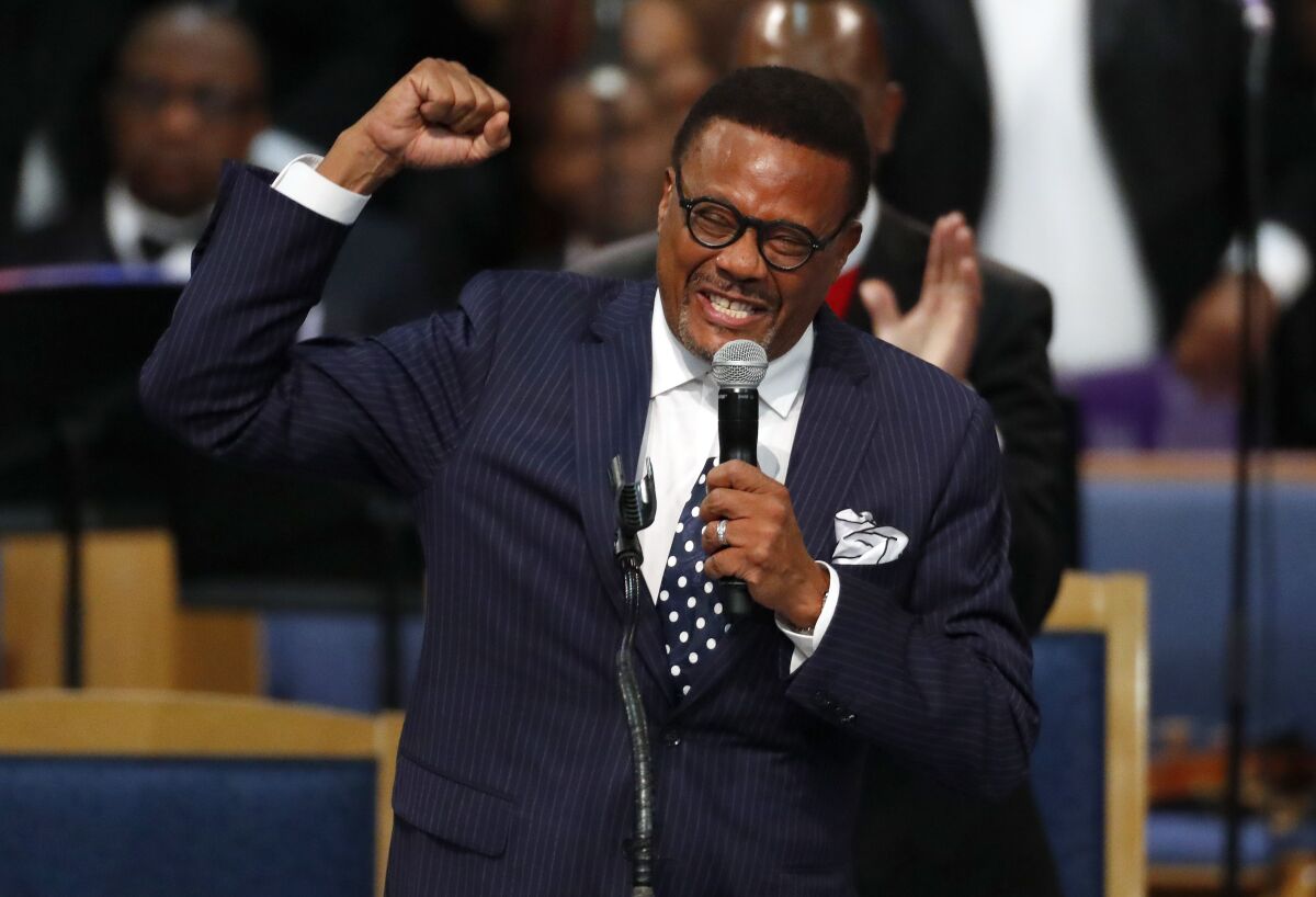 A man holds a fist in the air and with the other hand holds a microphone up to his mouth, cheering.