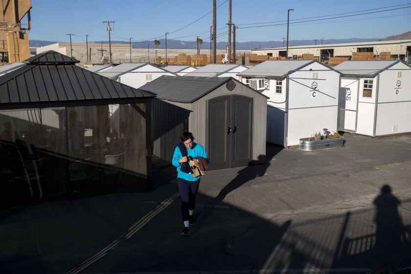 RIVERSIDE, CA - NOVEMBER 30, 2020: A resident of the the tiny home village walks to the common shower area on November 30, 2020 in Riverside, California. Los Angeles is embracing the idea of tiny homes to get homeless off the streets, but the buildings are sitting in storage.(Gina Ferazzi / Los Angeles Times)