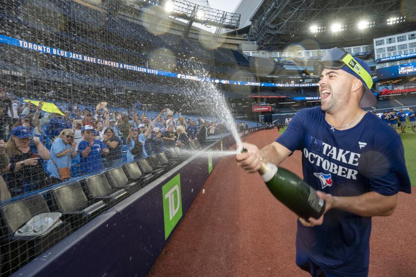 Toronto Blue Jays' Whit Merrifield, right, sprays down fans as they celebrate after clinching a berth in the AL wild card series following a baseball game against the Tampa Bay Rays in Toronto, Sunday, Oct. 1, 2023. (Frank Gunn/The Canadian Press via AP)