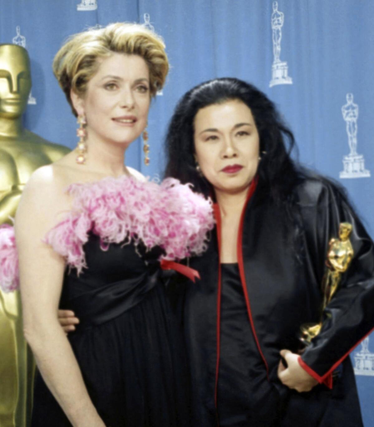 Actress Catherine Deneuve poses with Eiko Ishioka as she holds her Oscar for best costume design for "Bram Stoker's Dracula" backstage at the 1993 Academy Awards in Los Angeles.