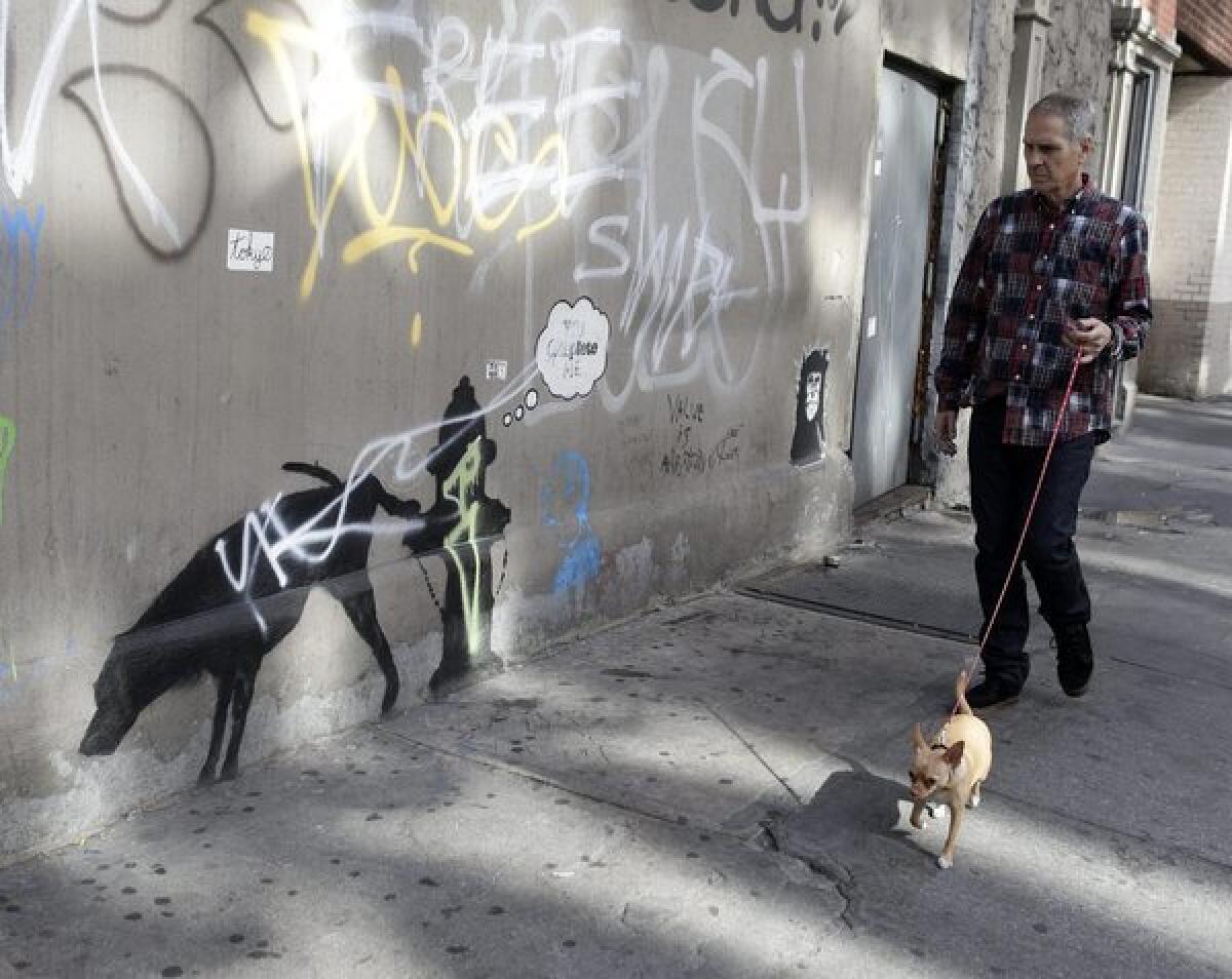 A man walking his dog in New York checks out a work by Banksy this week that has been defaced.