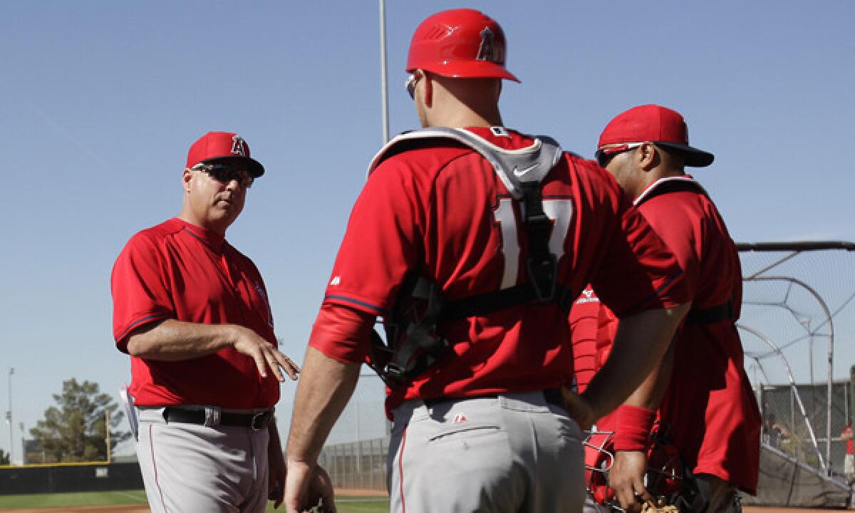 Angels Manager Mike Scioscia, left, speaks to his catchers during a spring-training practice session on Feb. 20. Scioscia understands the physical and mental demands his catchers face every game.