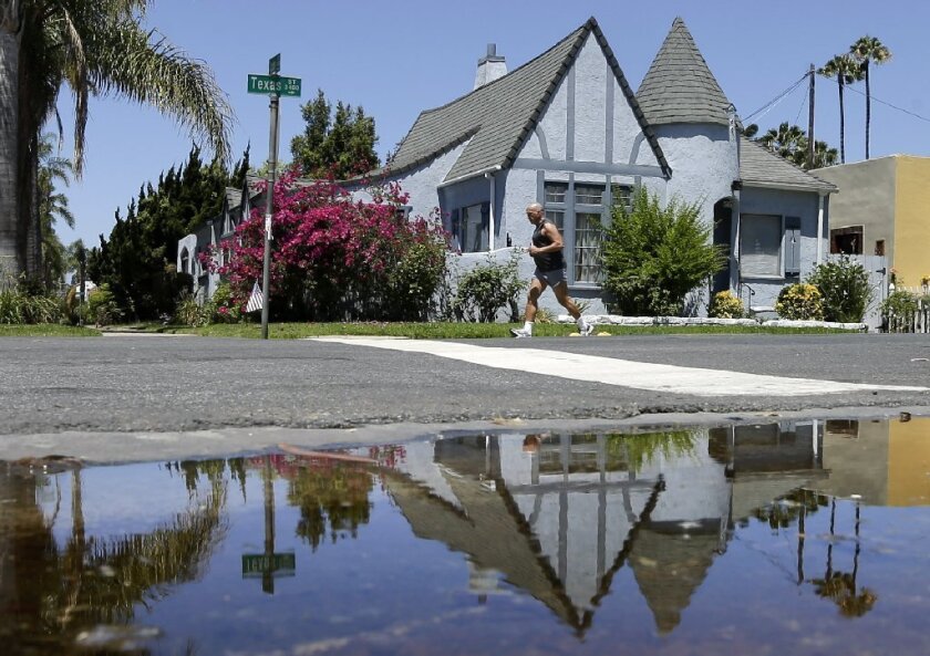 A house is reflected in a puddle of water from an over-irrigated yard in San Diego.