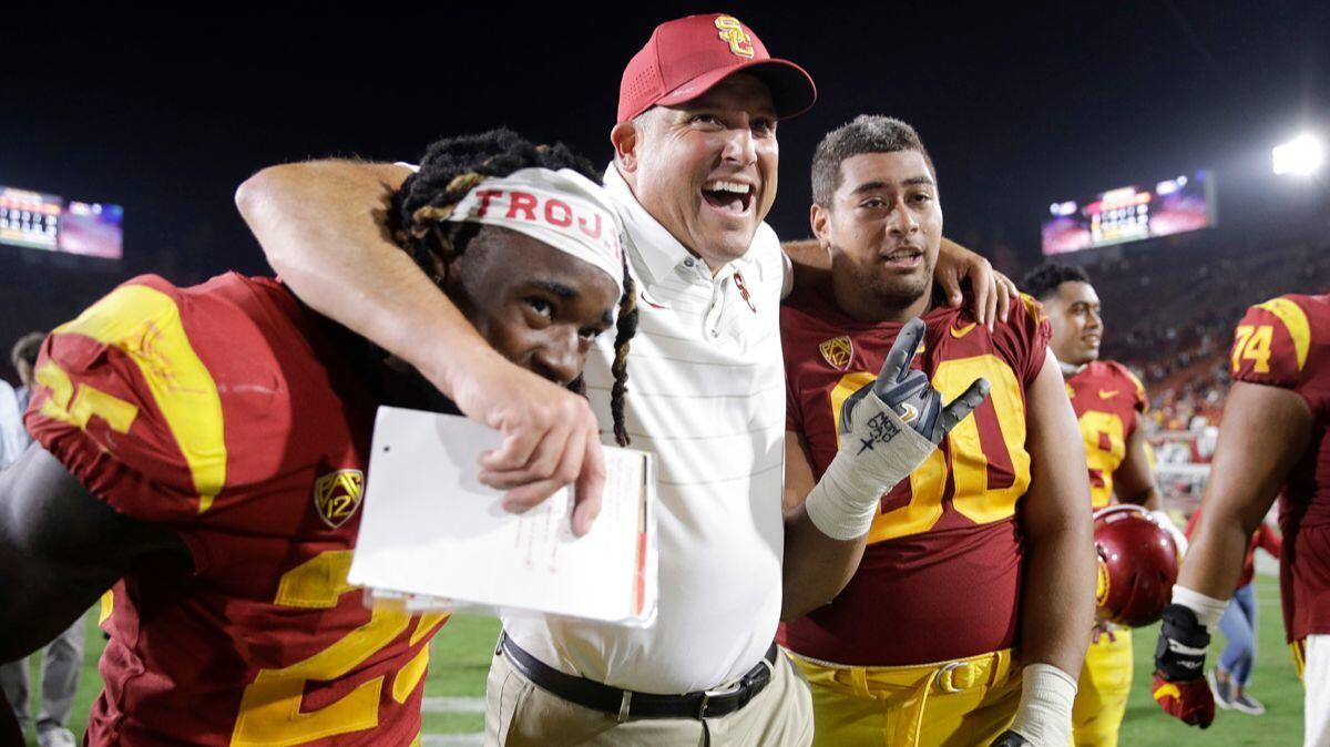 USC Coach Clay Helton, center, Ronald Jones II, left, and Viane Talamaivao celebrate the team's 42-24 win against Stanford, as they walk off the field on Sept. 9, 2017.