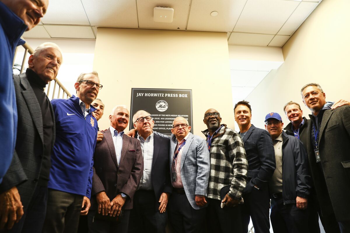 New York Mets staff and former players pose with Jay Horwitz as the press box is dedicated in his honor before the start of a baseball game against The Arizona Diamondbacks, Sunday, April 17, 2022, in New York. Horwitz, the team's media relations director from 1980 to 2018, is currently the team's vice president of alumni relations and team historian. (AP Photo/Jessie Alcheh)