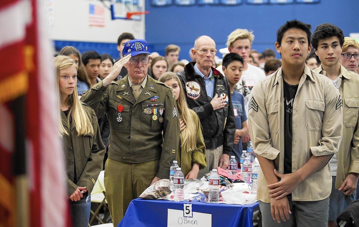 Dick O'Brien, a sergeant in the Army during World War II, salutes on Thursday as he stands among students who interviewed him for the Living History project at Corona del Mar High School.