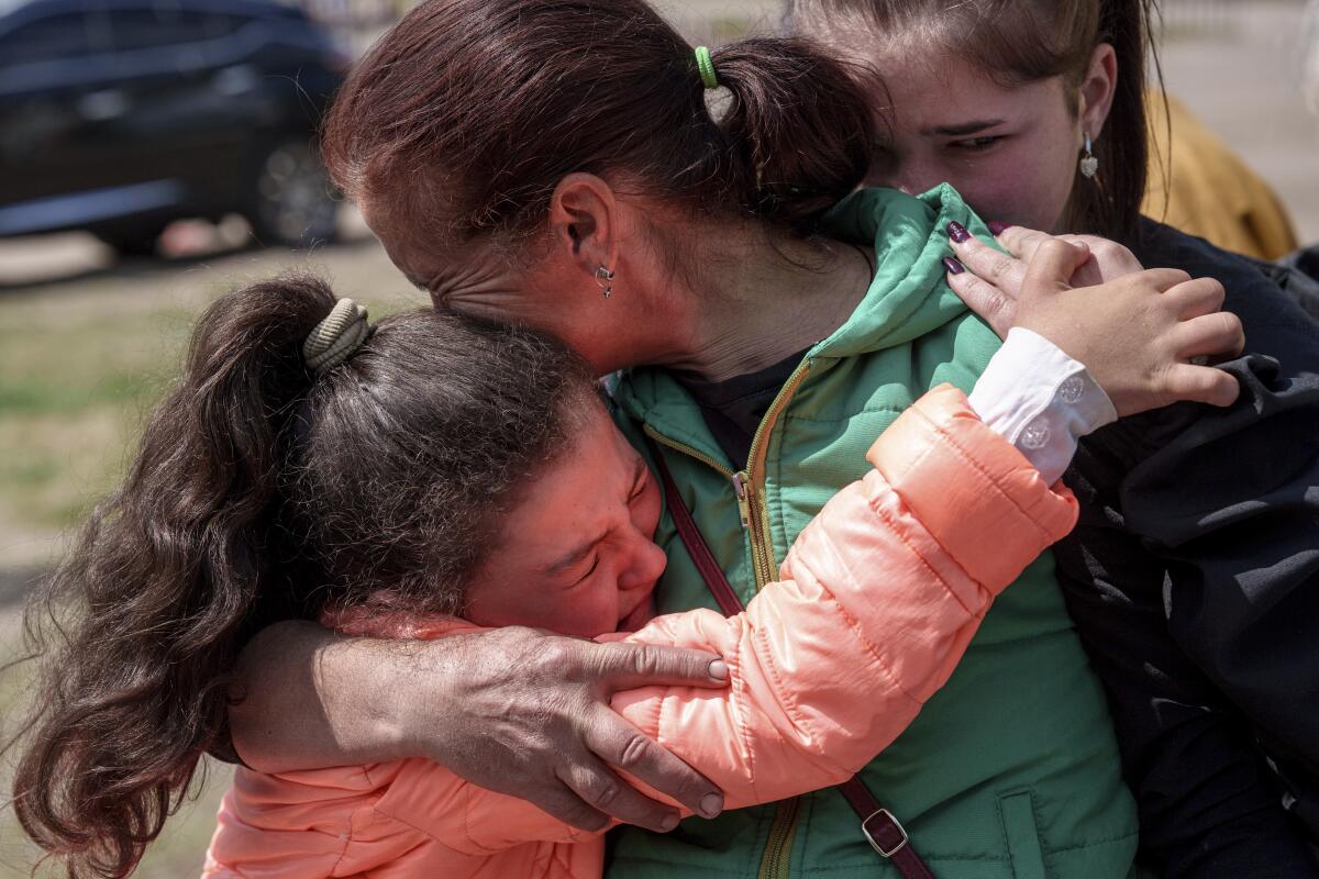 A Ukrainian child hugs her mother and cries after they evacuate.