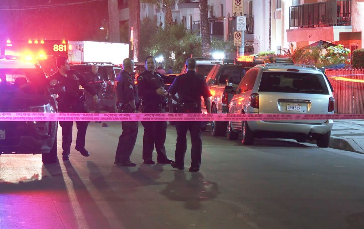 Uniformed police officers stand on the street behind police scene tape