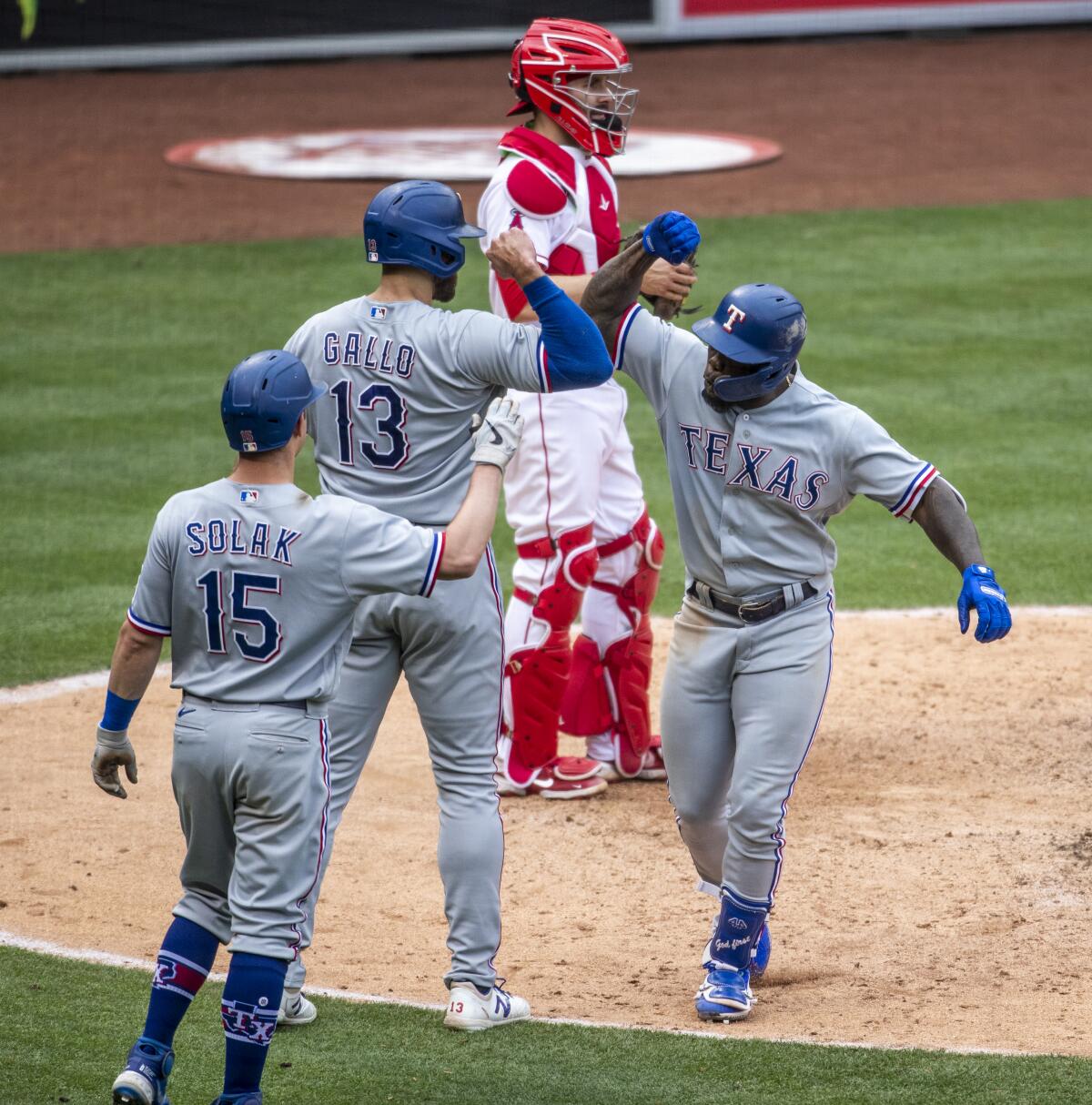 Texas Rangers Adolis Garcia is congratulated at the plate by center fielder Joey Gallo and second baseman Nick Solak.
