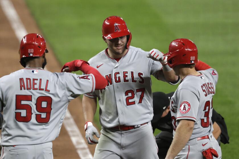 Los Angeles Angels' Mike Trout (27) is met at home by Jo Adell (59) and Max Stassi on his three-run home run against the Seattle Mariners during the seventh inning of a baseball game Wednesday, Aug. 5, 2020, in Seattle. (AP Photo/Elaine Thompson)