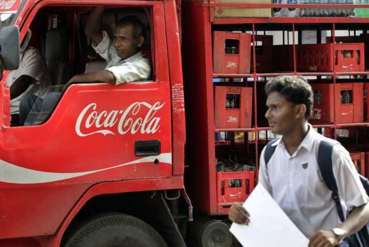 A man walks past a truck that distributes Coca Cola in Mumbai, India. The world's biggest beverage maker said Tuesday that it will invest an additional $3 billion in India through 2020.