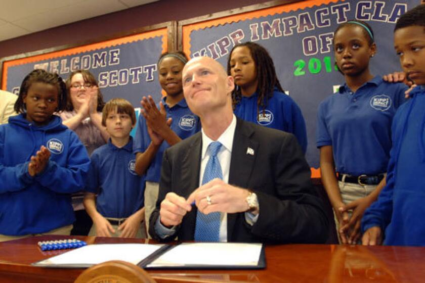 Florida Gov. Rick Scott signs his controversial teacher-merit pay law, surrounded by Kipp Middle School students in Jacksonville.