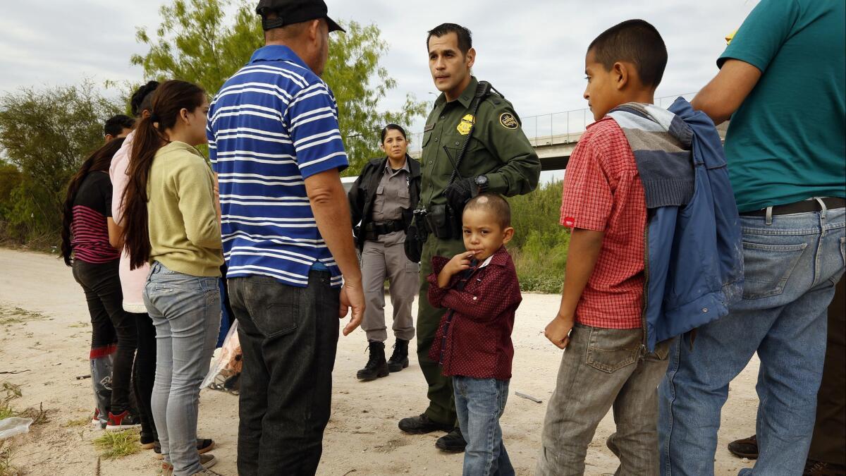 Ely Fernandez of Honduras is questioned by Border Patrol Agent Robert Rodriguez after being detained for crossing the border illegally in March with his 5-year-old son, Bryan, center.
