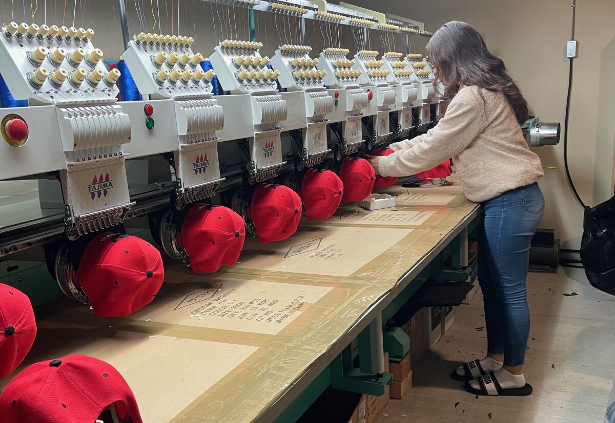 Stephanie Contreras-Reyes loads snapback hats onto an embroidery machine 