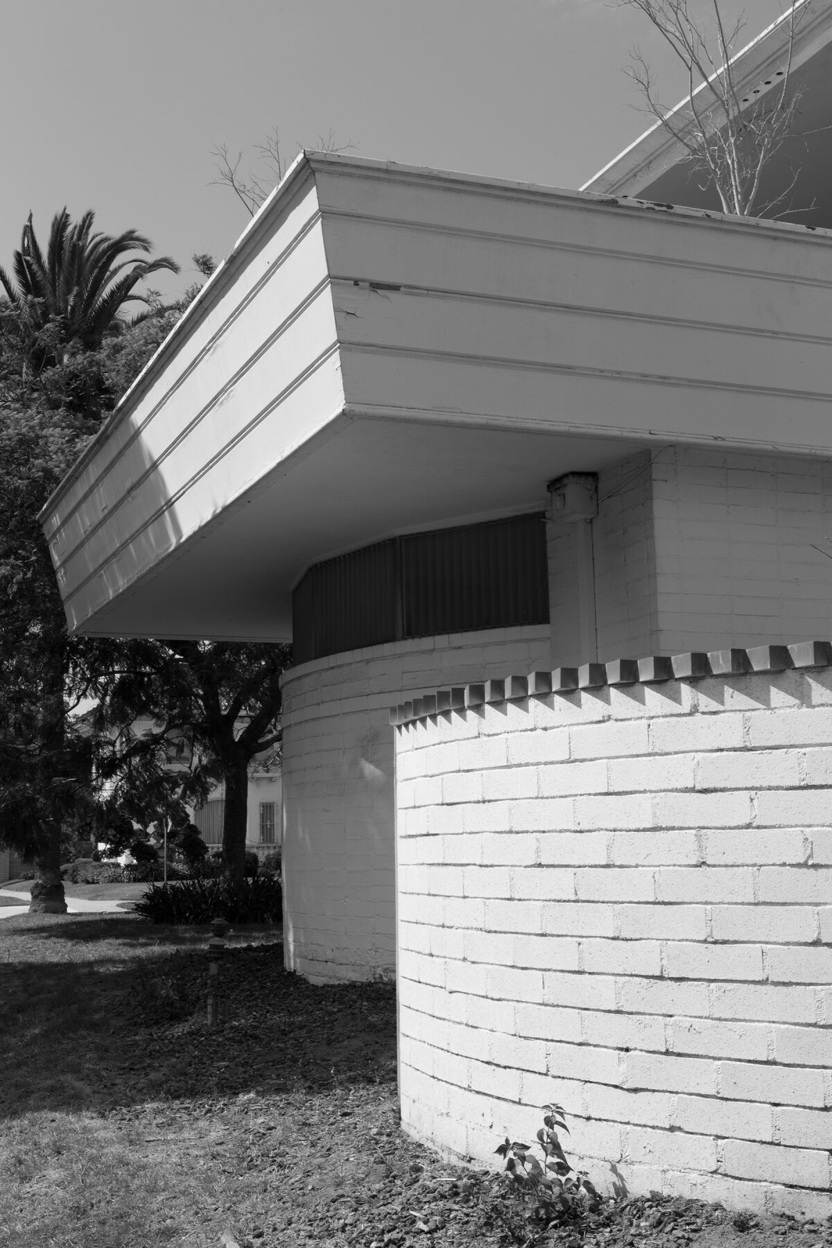 A black-and-white image of the Paul Williams Residence shows a curving wall with a serrated edge.