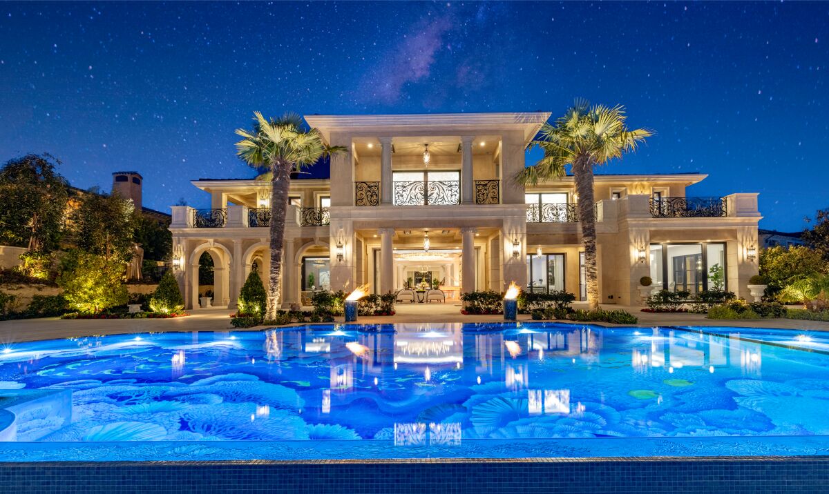 A two-story mansion with a pool in front.