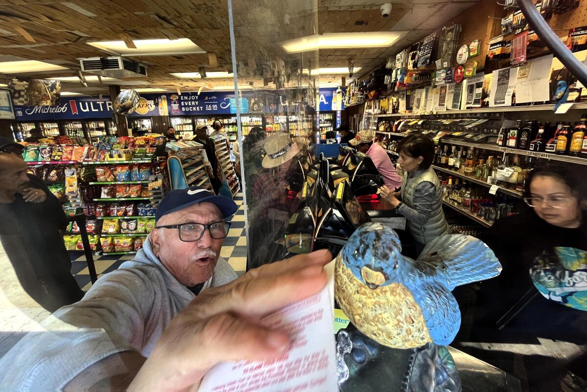 A customer holds lottery tickets up to a metal bluebird.