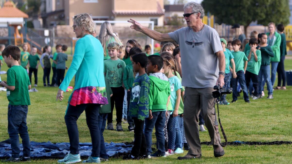 Artist Daniel Dancer directs Woodland Elementary School students to their spots to form the image of a dragon for their “Art for the Sky” project Thursday at the school in Costa Mesa.