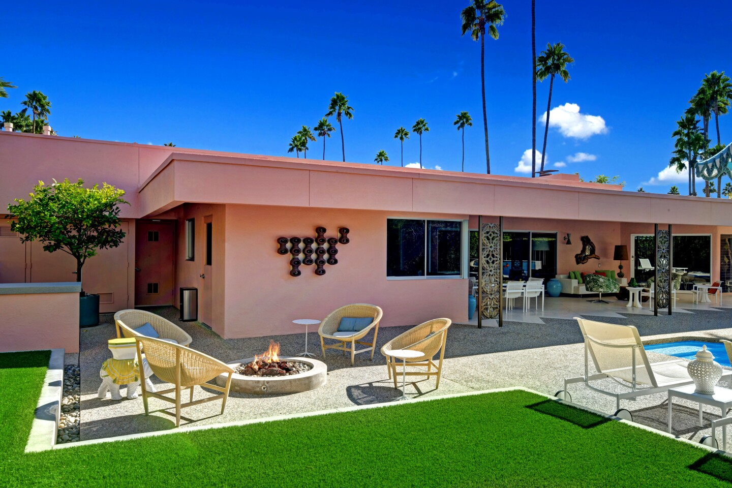Designed by local architects Albert Frey and Robson Chambers, the pink-hued residence unfolds as a series of interconnected boxes. The home was built in 1964 for radio and TV owner Carl Haymond and his wife, Margaret. Listed for $2.995 million, the house features a series of aluminum screens that provide privacy while diffusing natural light. The screens were designed by John deKoven Hill, an associate of Frank Lloyd Wright. The single-story house features travertine and terrazzo tile floors, walls of glass and walnut built-ins. The steel cabinetry in the kitchen is original.