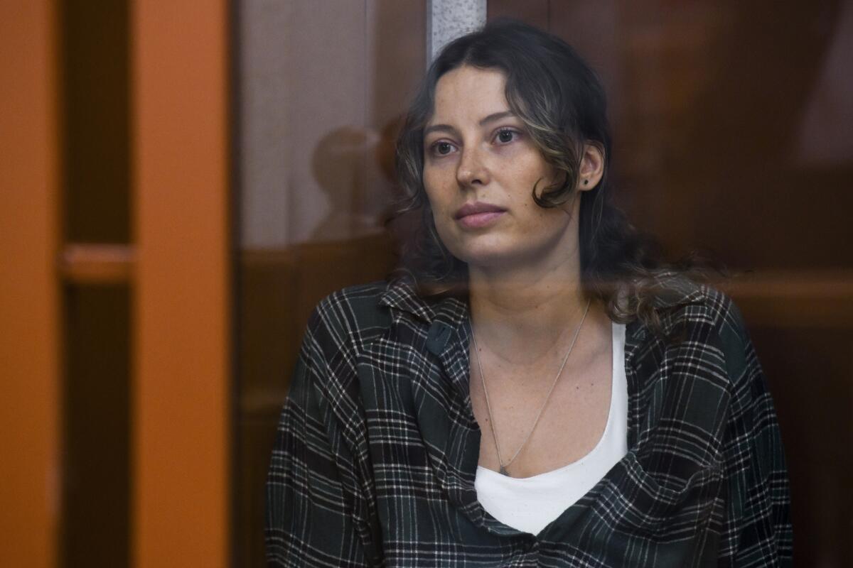 A woman sits in a glass cage in a Russian court.