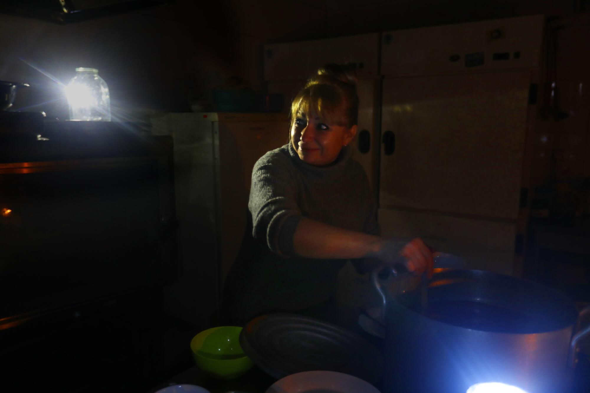 A woman cooks by candlelight.  