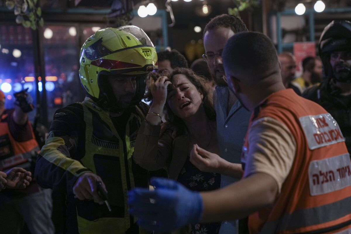 A woman reacts at the scene of a shooting attack In Tel Aviv, Israel, Thursday, April 7, 2022. Israeli police say several people were wounded in a shooting in central Tel Aviv. The shooting on Thursday evening occurred in a crowded area with several bars and restaurants. (AP Photo/Ariel Schalit)