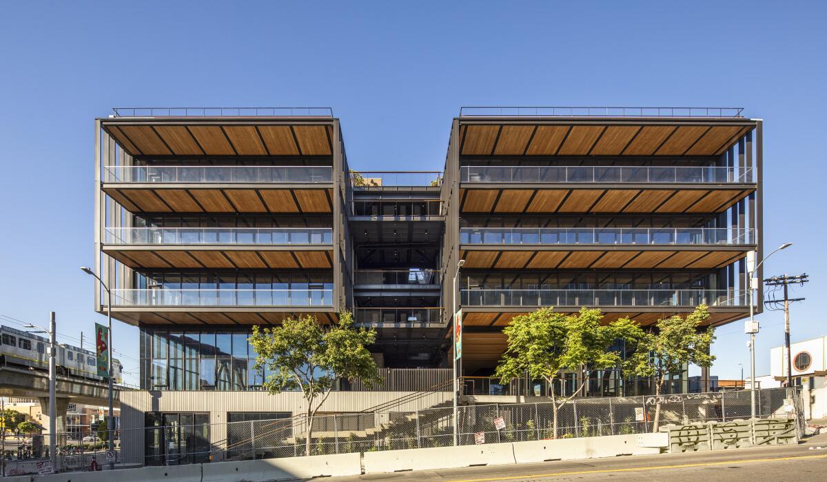 The facade of a four-story building is illuminated by sunlight, revealing wood supporting the floor plates.