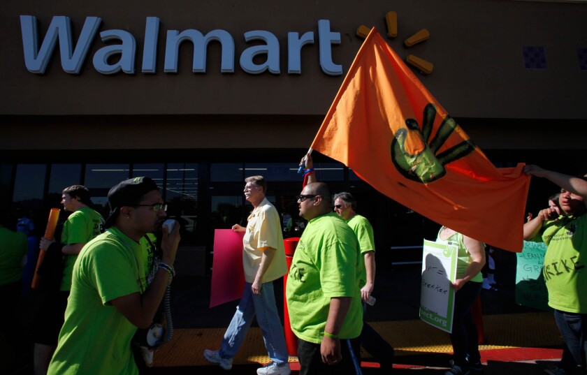 Wal-Mart worker Anthony Goytia carries an "our Wal-Mart" flag outside a Paramount store alongside some 200 employees and supporters who protested for better working conditions, higher salaries and no retaliation for those who speak out against the company.