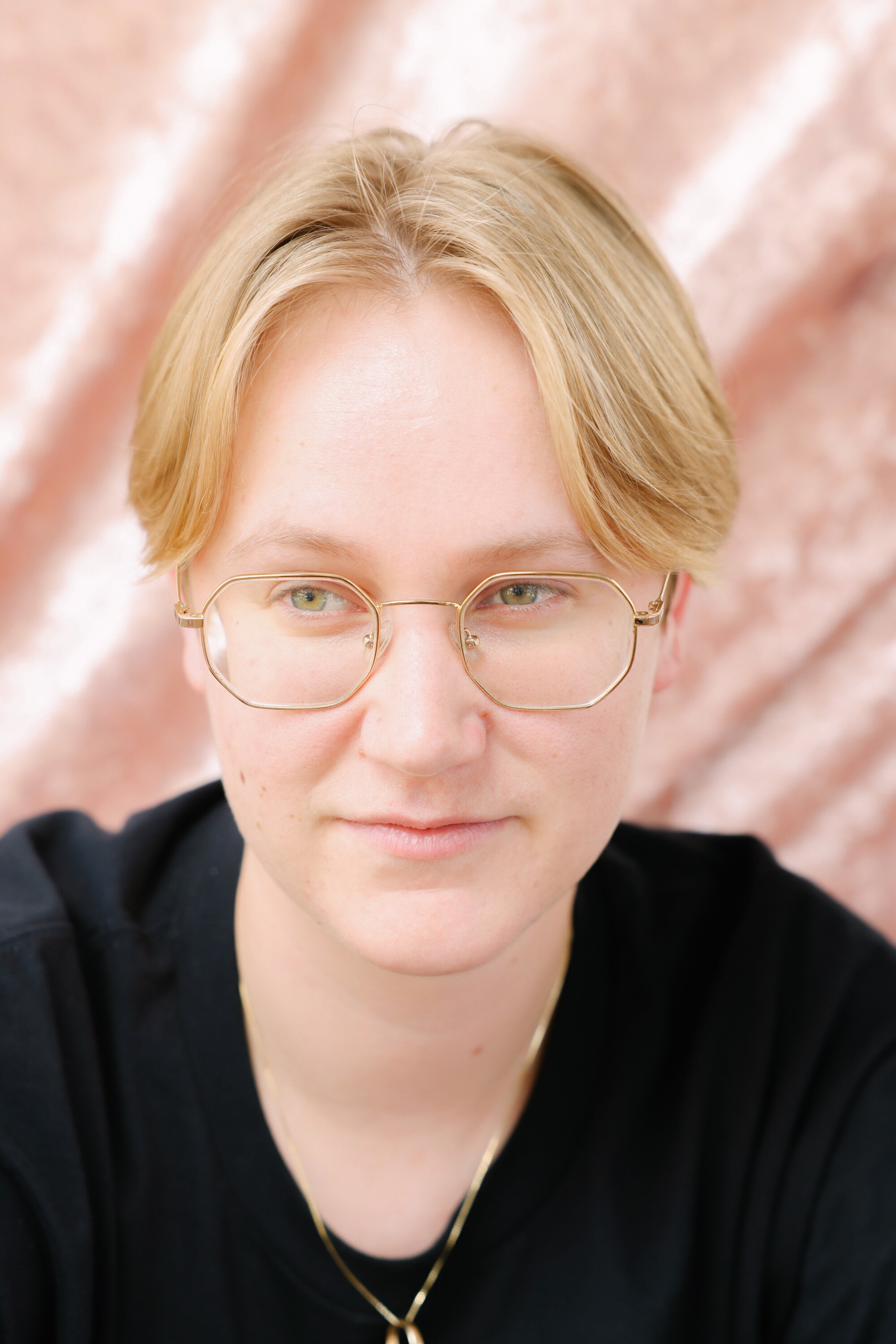 A person with glasses and short blond hair poses for a portrait