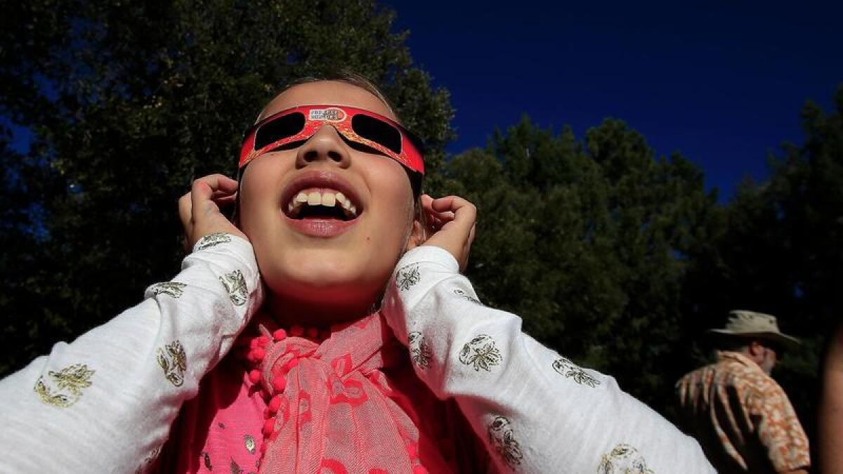 Eliza Monsalvez looks through solar glasses to see a partial eclipse of the sun at the Mt. Wilson Observatory in 2014. The observatory will welcome eclipse fans again on Monday.
