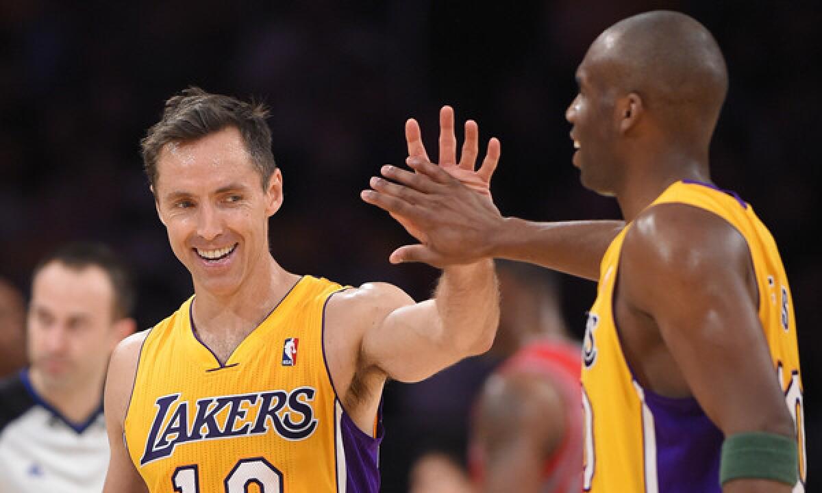 Lakers point guard Steve Nash, left, is congratulated by guard Jodie Meeks after moving into a tie for third place on the NBA's career assists list. Nash later took sole possession of third place on the list during the Lakers' 145-130 loss to the Houston Rockets.
