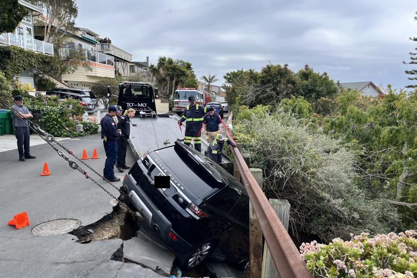 Crews work to pull a Range Rover out of a sinkhole on Sunset Avenue in Laguna Beach on Sunday, March 5, 2023.