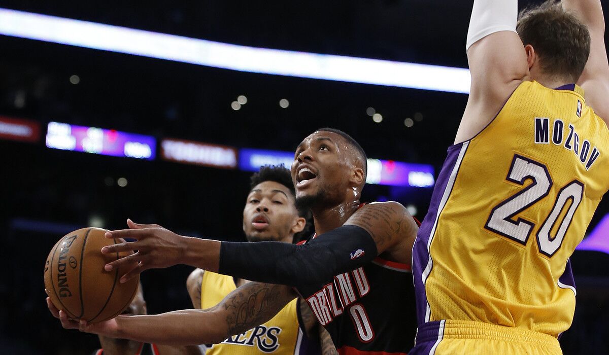 Portland Trail Blazers guard Damian Lillard (0) shoots between Lakers forward Brandon Ingram (14) and center Timofey Mozgov (20) during the first half of an exhibition game at Staples Center.