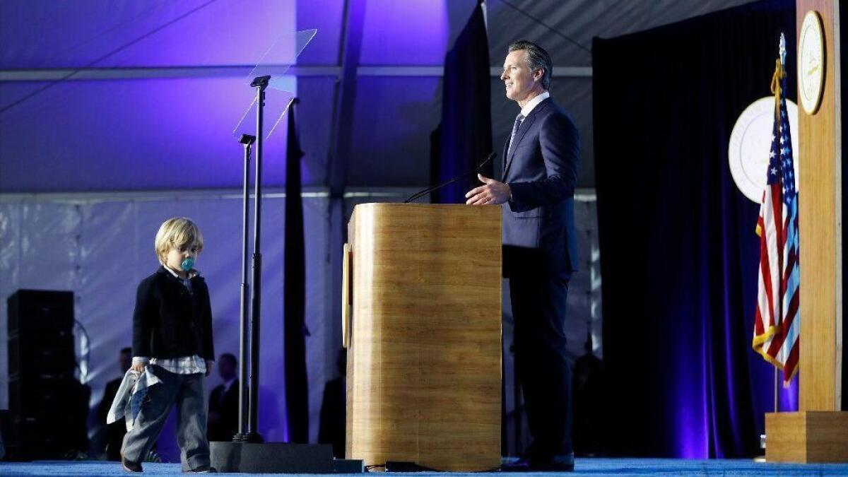 Gov. Gavin Newsom delivers his inaugural address as his son Dutch, 2, walks onstage Monday.