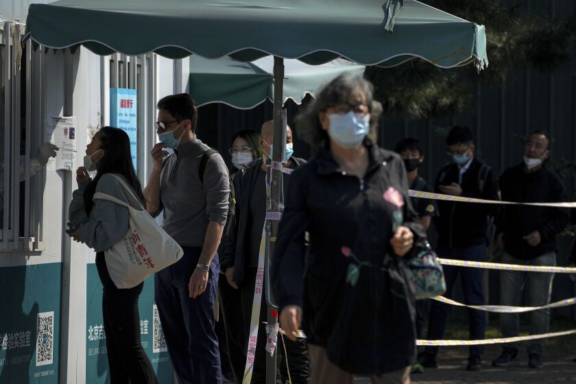 Residents line up to get their routine COVID-19 throat swabs at a coronavirus testing site in Beijing, Thursday, Oct. 6, 2022. Sprawling Xinjiang is the latest Chinese region to be hit with sweeping COVID-19 travel restrictions, as China further ratchets up control measures ahead of a key Communist Party congress later this month. (AP Photo/Andy Wong)