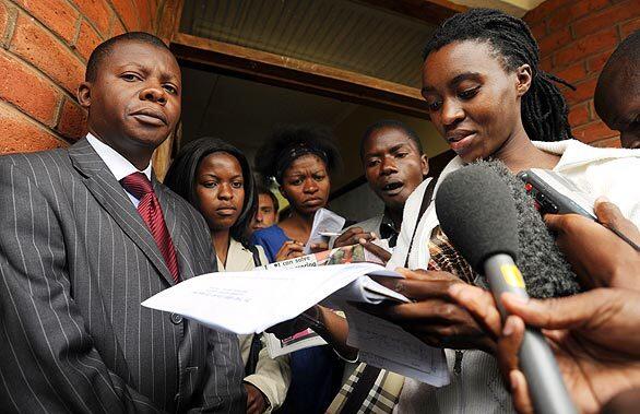 Journalist Deborah Nyangulu, right, reads the ruling denying Madonna's adoption. At left is Kenan Manda, senior deputy registrar at High Court of Malawi.