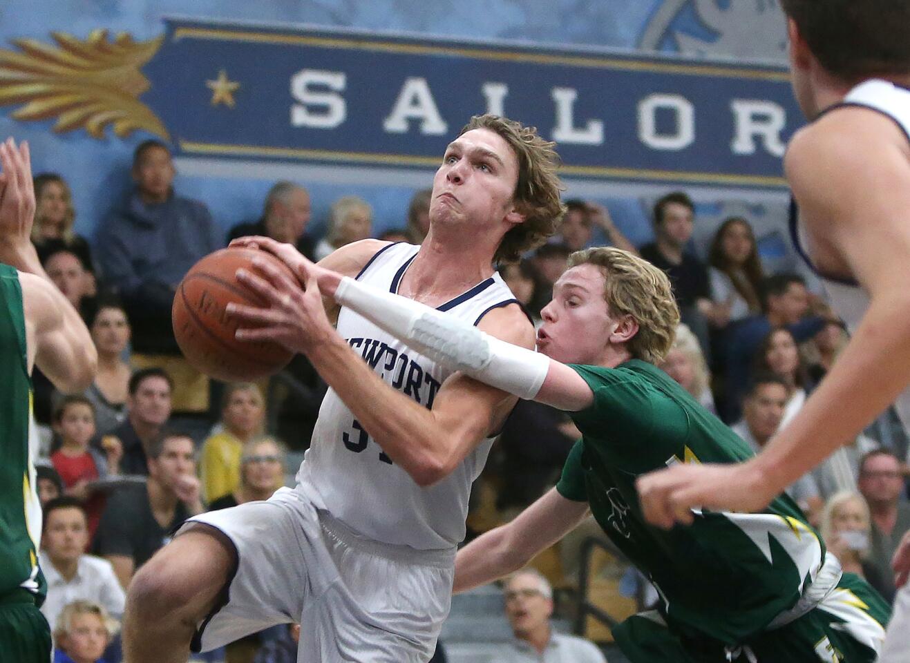 Newport Harbor's Dayne Chalmers drives the basket for a lay-up as Edison's Justin Strauss tries to stop him in Surf League boys' basketball game on Friday.